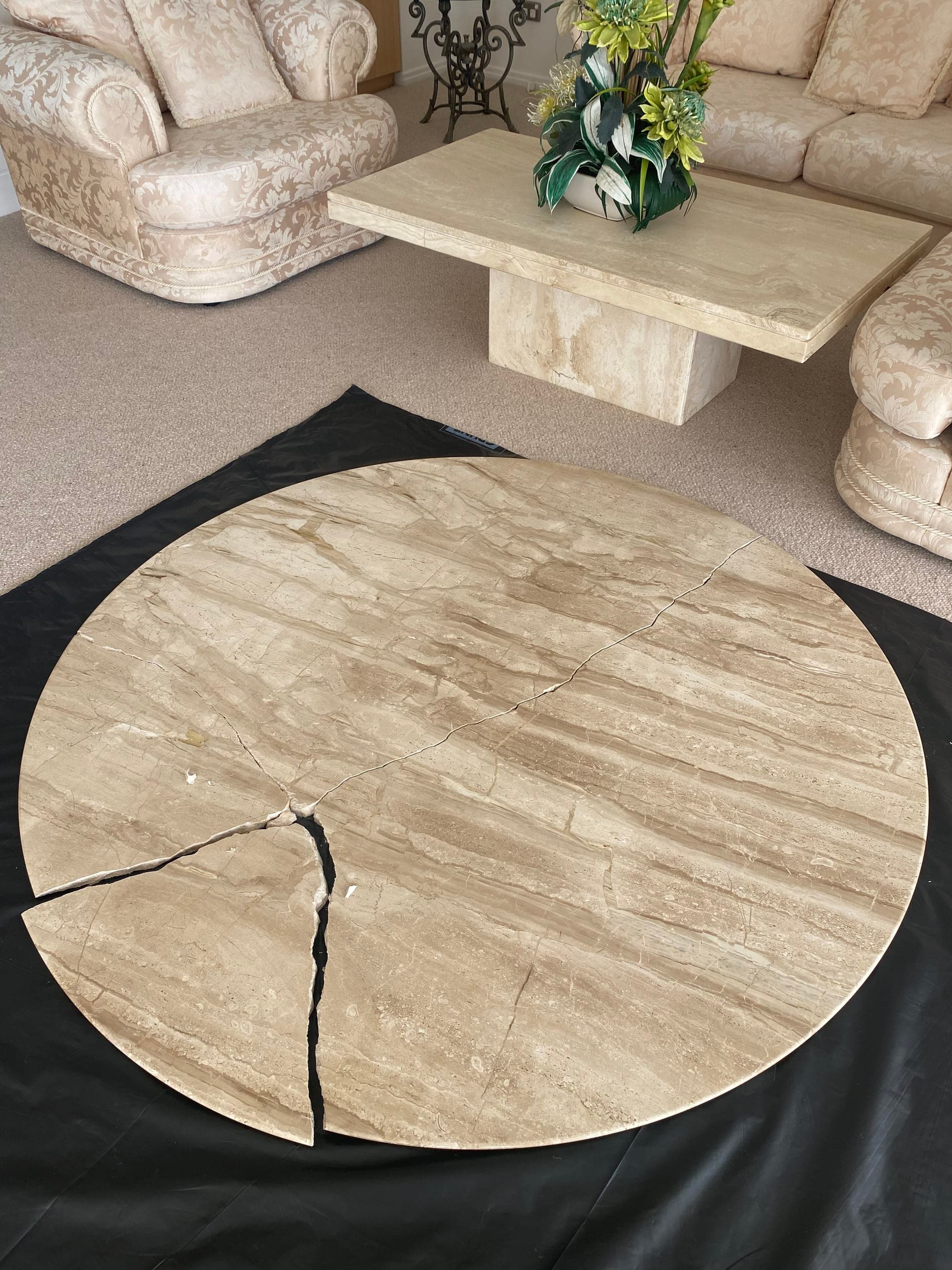 Round natural stone top laid on a black protective sheet with a crack running across it