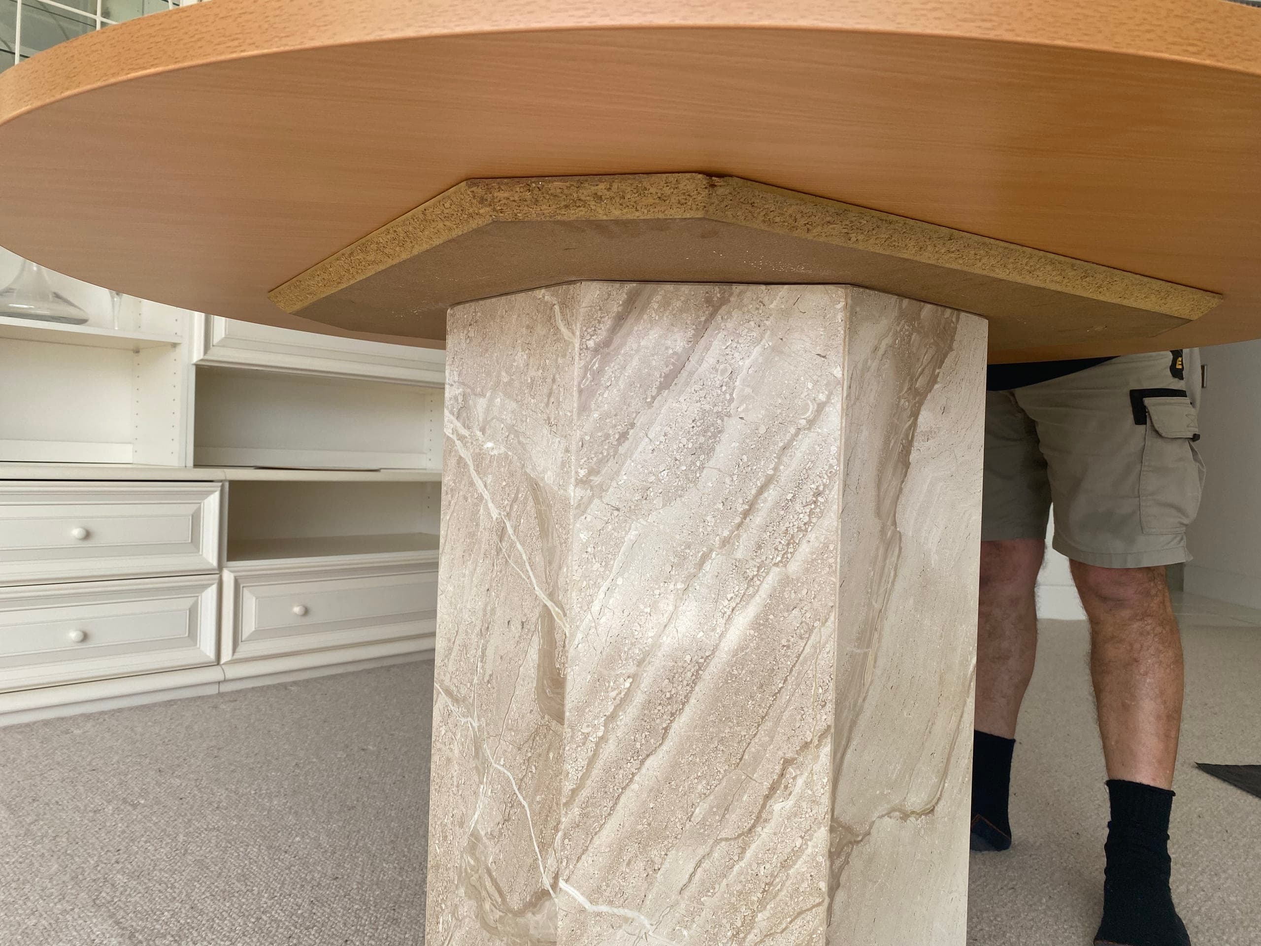 Edge of the round timber top resting on the tapered stone pedestal column