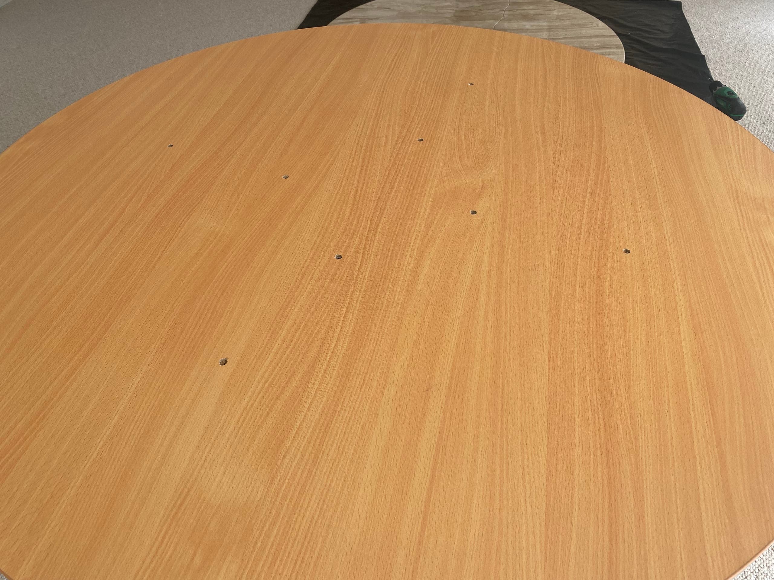 Close-up of the round timber top surface showing small fixing holes