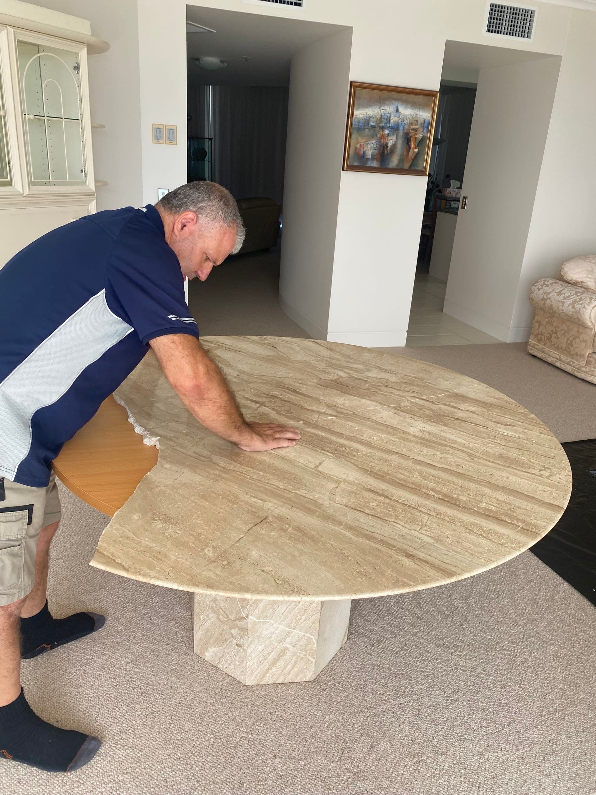 Technician positioning a broken piece of the stone top onto the pedestal base