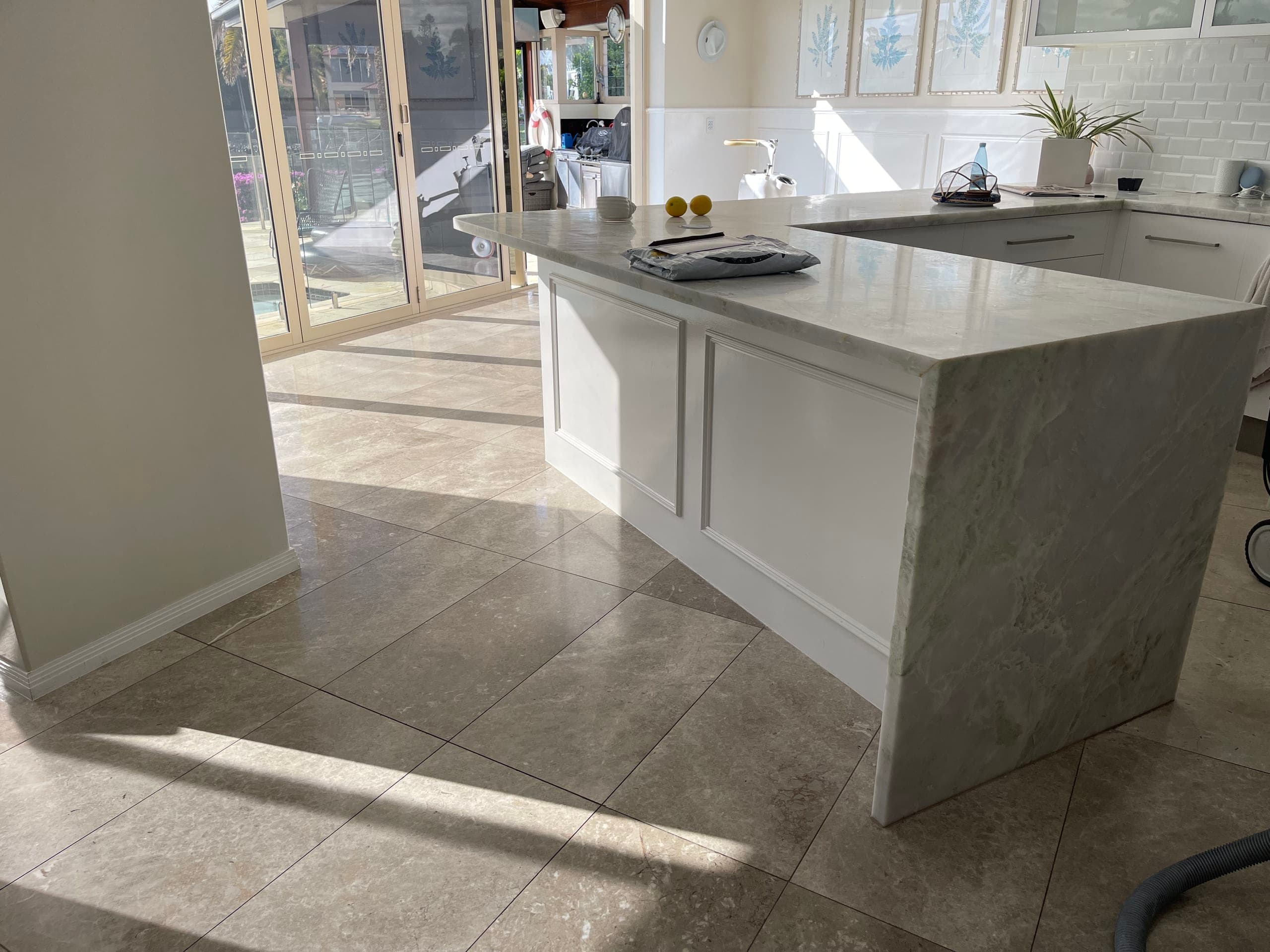 Dull grey marble floor in the dining and kitchen area before restoration, beside the stone island bench