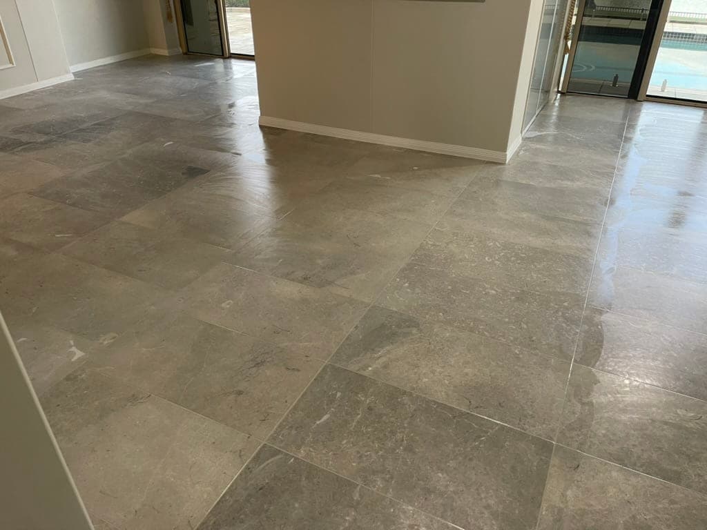 Grey marble floor with refilled joints and grinding equipment mid-restoration