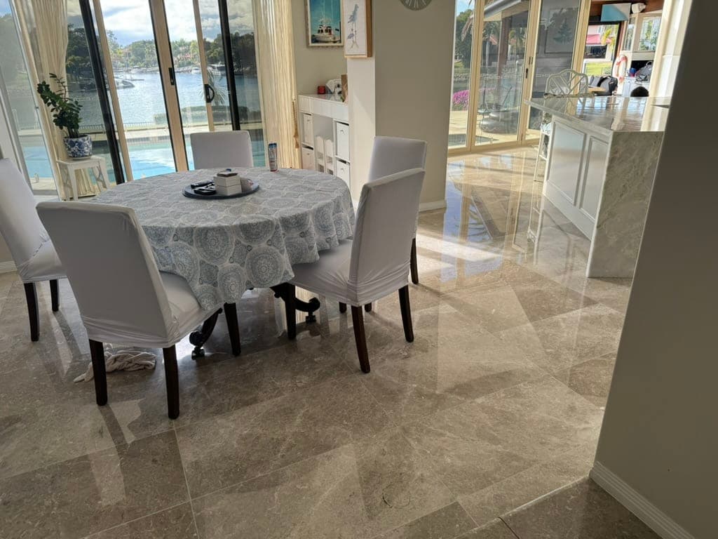 Polished marble floor beneath the dining setting, reflecting the waterfront windows