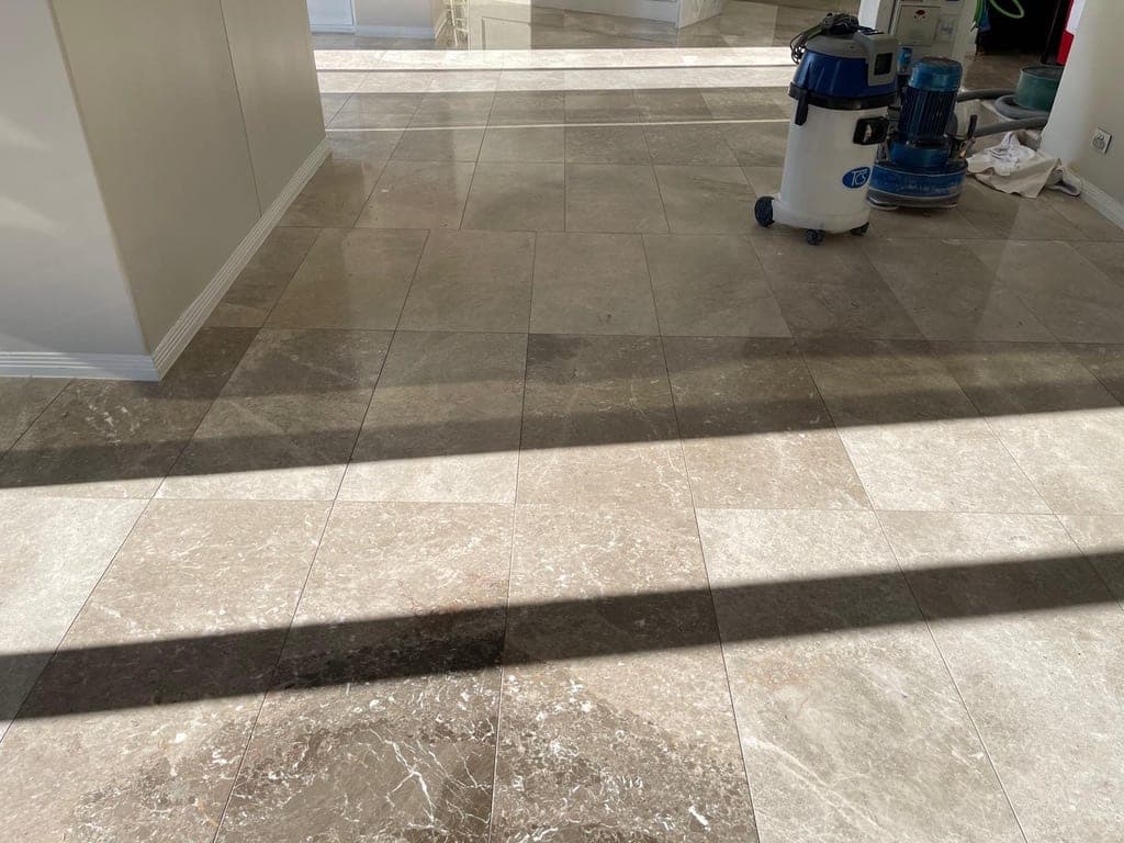 Close view of the tired grey marble floor with visible wear and surface debris before grinding