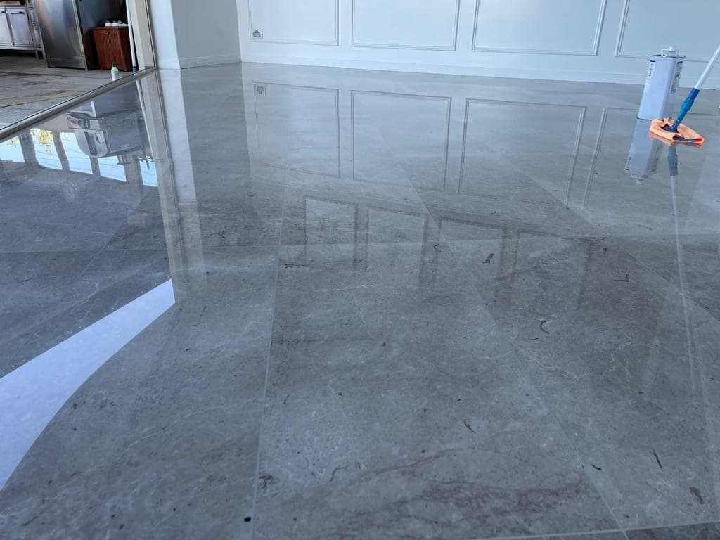 The same grey marble dining-area floor after restoration, polished and sealed to a reflective finish