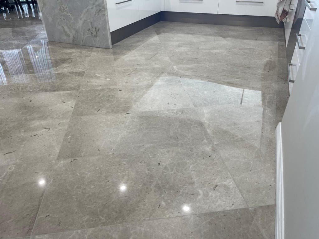 The same grey marble kitchen floor after restoration, polished and sealed to a reflective finish