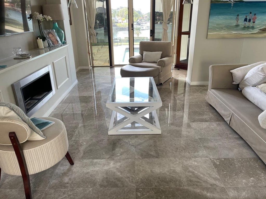 The same grey marble living-area floor after restoration, polished to a high-gloss reflective finish