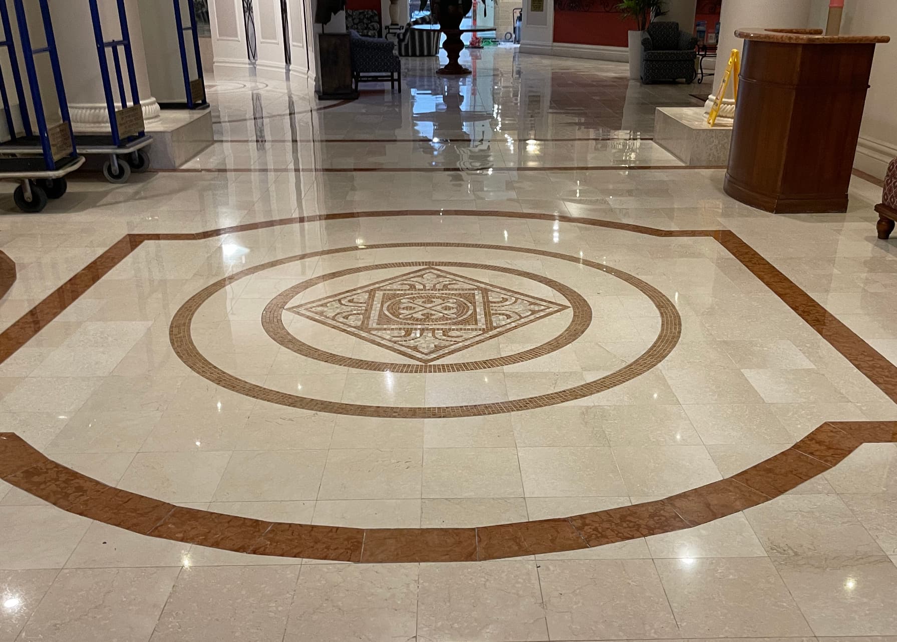 Restored hotel lobby marble floor with a mosaic medallion and rosso stone border