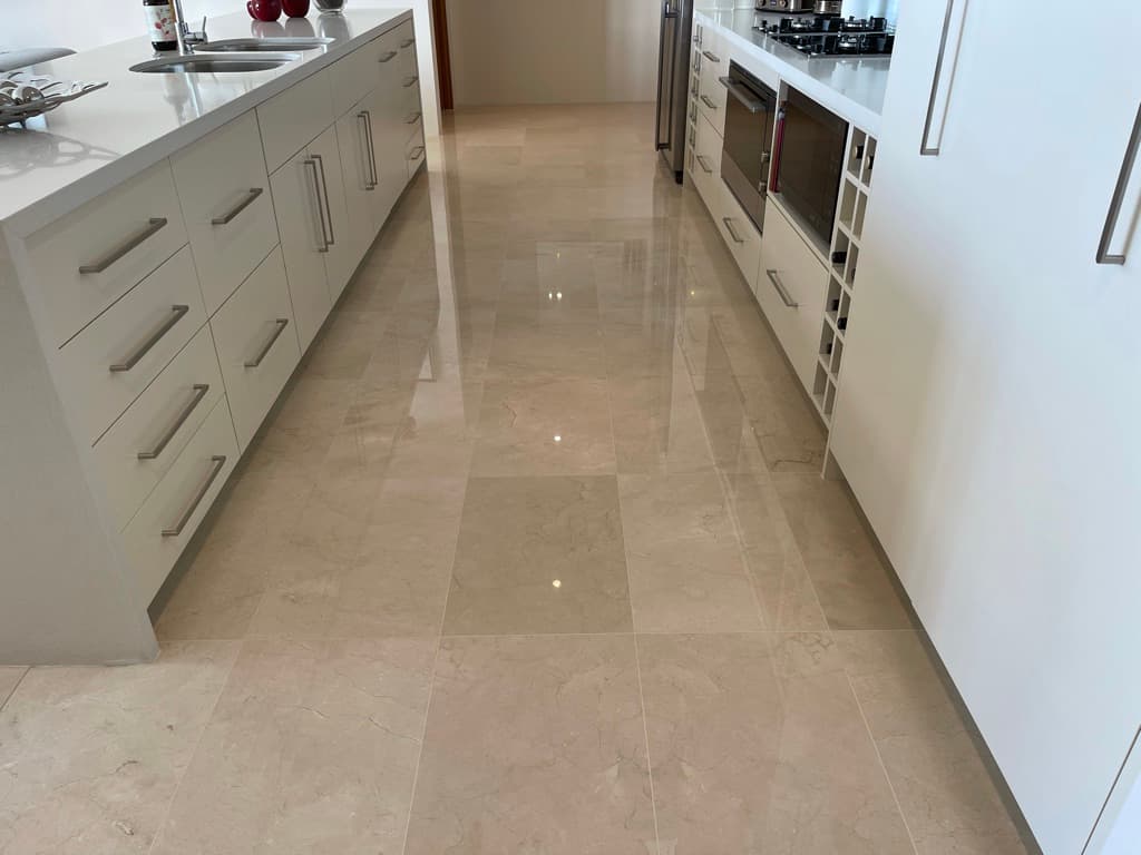 Polished marble kitchen floor reflecting cabinetry after full restoration